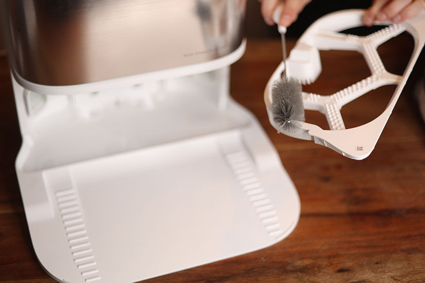 Чистящая ванночка базовой станции Dreame L10s Ultra очищается с помощью чистящей щетки.